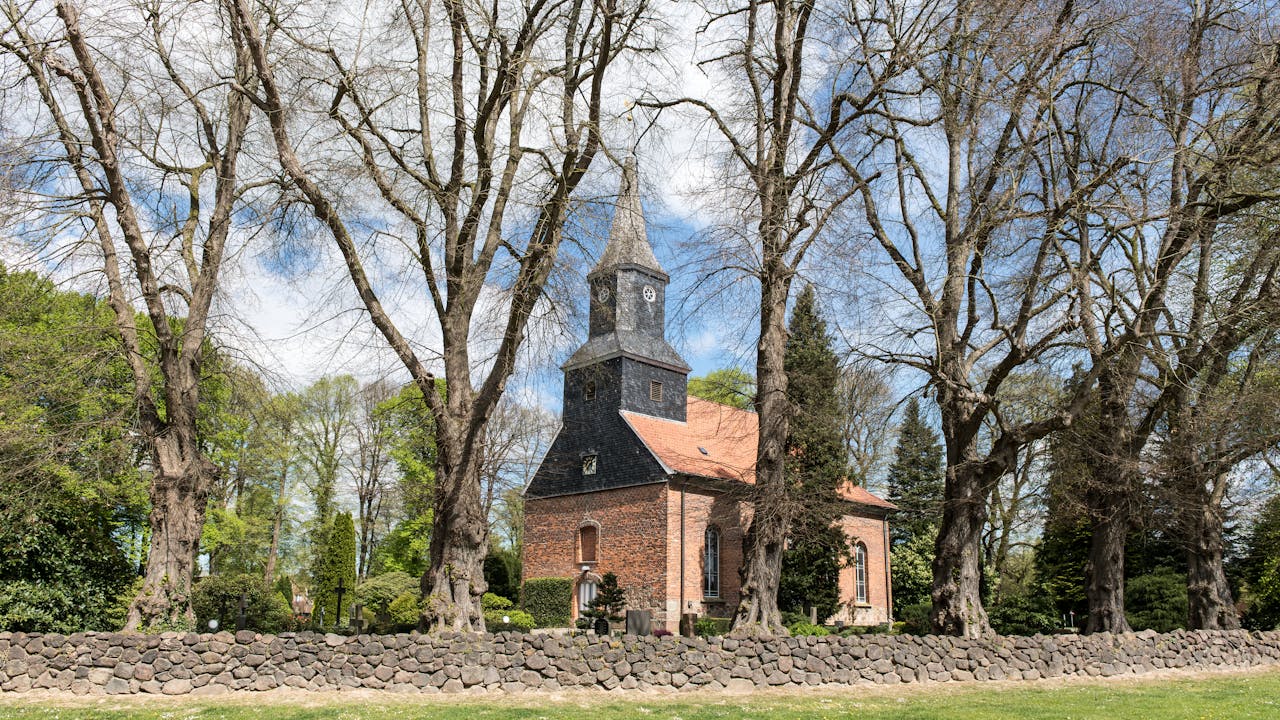 Crafting Captivating Headlines: Your awesome post title goes here Scenic view of a historic brick chapel in Brunstorf, surrounded by trees and stone wall.
