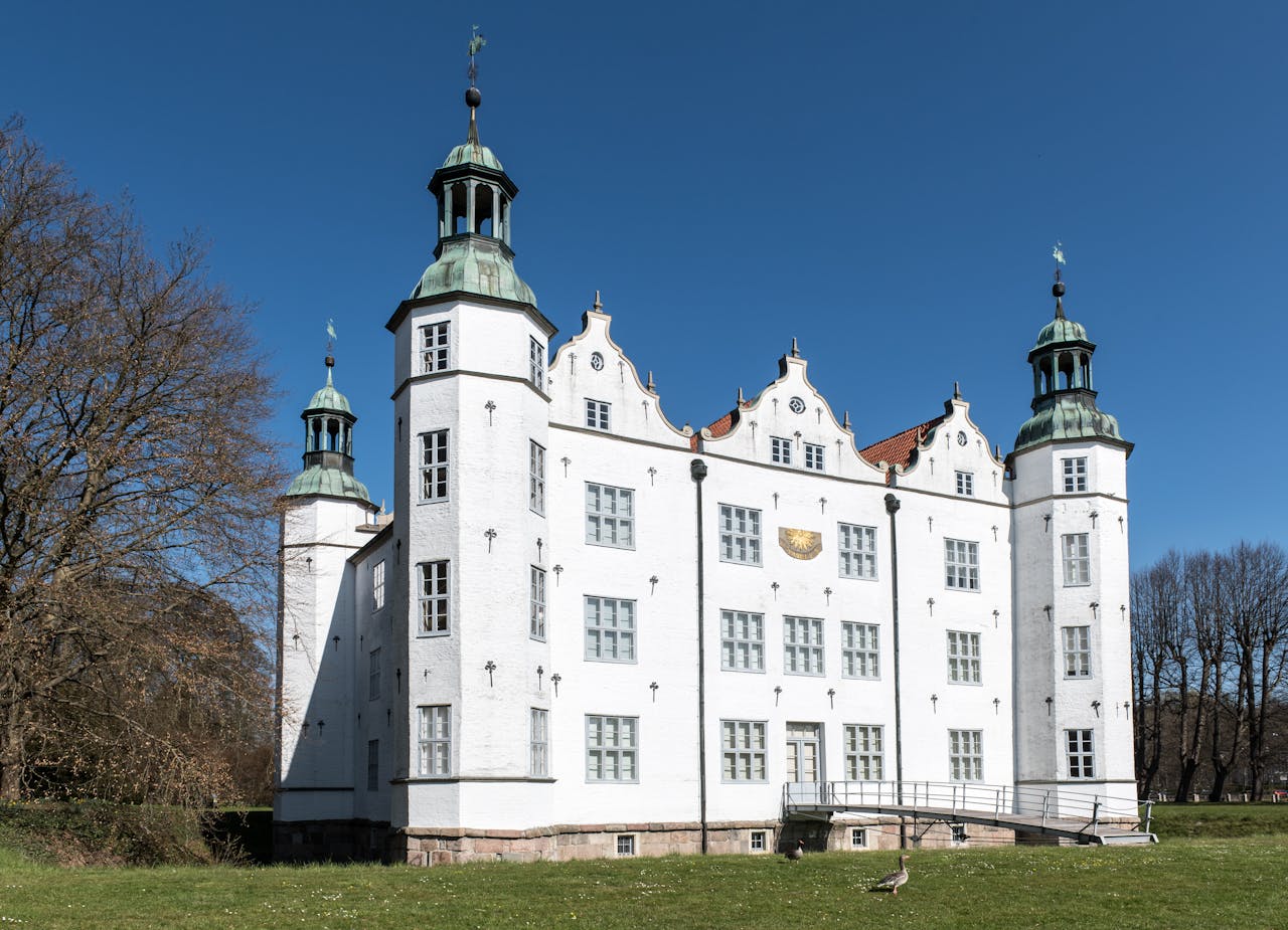 The Art of Drawing Readers In: Your attractive post title goes here A beautiful view of Ahrensburg Castle in Germany under a clear blue sky, showcasing its historic architecture.